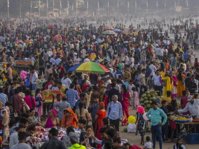 People crowd at the Juhu beach on the Arabian Sea coast in Mumbai, India, Sunday, Nov. 13, 2022. The 8 billionth baby on Earth is about to be born on a planet that is getting hotter. But experts in climate science and population both say the two issues aren't quite as connected as they seem. (AP Photo/Rafiq Maqbool)