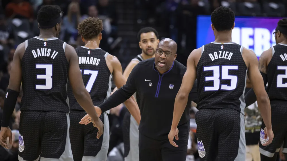 Sacramento Kings coach Mike Brown greets guard Terence Davis (3) and guard PJ Dozier (35) during a timeout in the first half of the team's NBA basketball game against the Golden State Warriors in Sacramento, Calif., Friday, April 7, 2023. (AP Photo/José Luis Villegas)
