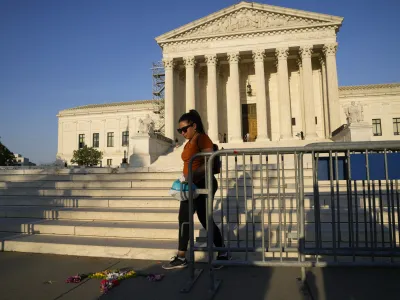 A person walks by flowers that are in the shape of a uterus outside the Supreme Court on Friday, April 21, 2023, in Washington. The Supreme Court has preserved women's access to a drug used in the most common method of abortion, rejecting lower-court restrictions while a lawsuit continues. The justices on Friday granted emergency requests from the Biden administration and New York-based Danco Laboratories, maker of the drug mifepristone. (AP Photo/Jacquelyn Martin)