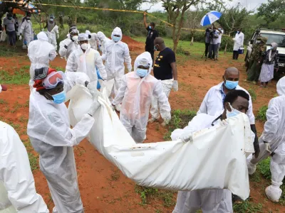 Forensic experts and homicide detectives carry the bodies of suspected members of a Christian cult named as Good News International Church, who believed they would go to heaven if they starved themselves to death, after their remains were exhumed from their graves in Shakahola forest of Kilifi county, Kenya April 22, 2023. REUTERS/Stringer