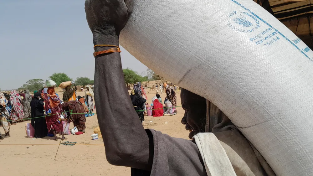 A worker of World Food Programme (WFP) carries a bag of relief grains to be distributed to Sudanese refugees who have fled the violence in their country, near the border between Sudan and Chad, in Koufroun, Chad April 28, 2023. REUTERS/Mahamat Ramadane