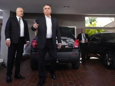 Former Brazilian President Jair Bolsonaro speaks to the press outside his house after Federal Police agents carried out a search and seizure warrant in Brasilia, Brazil, Wednesday, May 3, 2023. When asked about the search of Bolsonaro's home in Brasilia, the Federal Police press office gave a statement saying officers were carrying out searches and arrests related to the introduction of fraudulent data related to the COVID-19 vaccine into the nation's health system. (AP Photo/Eraldo Peres)