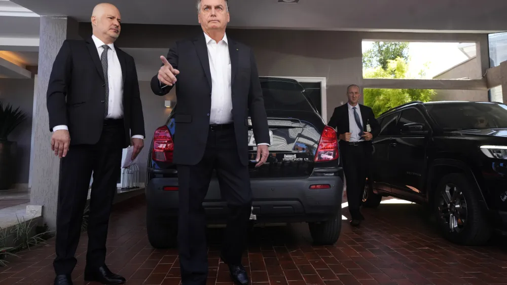 Former Brazilian President Jair Bolsonaro speaks to the press outside his house after Federal Police agents carried out a search and seizure warrant in Brasilia, Brazil, Wednesday, May 3, 2023. When asked about the search of Bolsonaro's home in Brasilia, the Federal Police press office gave a statement saying officers were carrying out searches and arrests related to the introduction of fraudulent data related to the COVID-19 vaccine into the nation's health system. (AP Photo/Eraldo Peres)