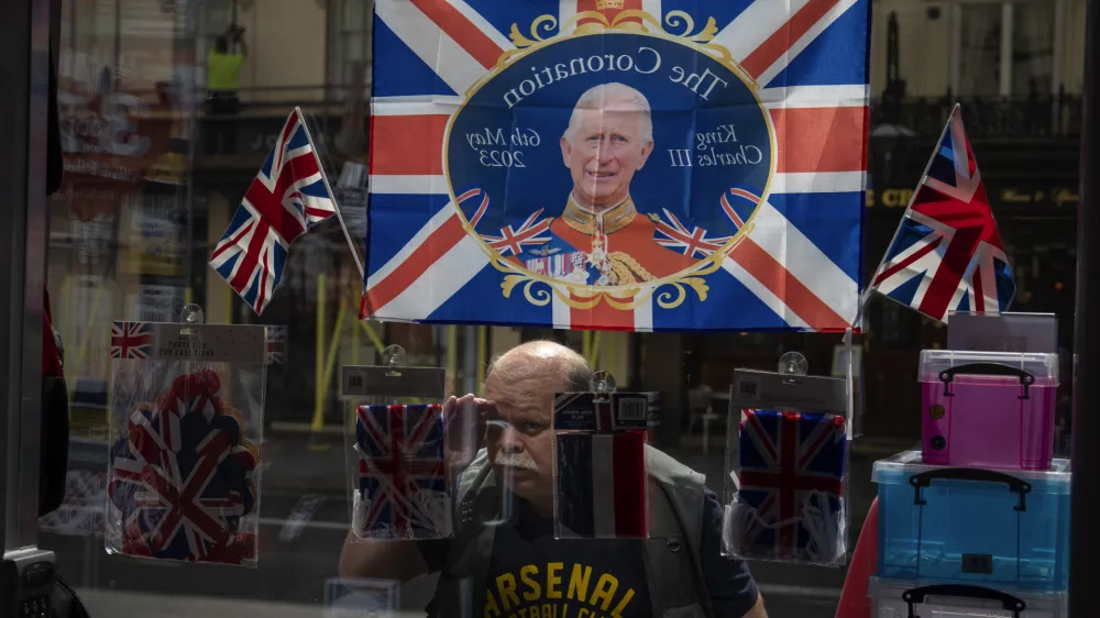 A man looks inside a souvenir shop decorated with a flag commemorating the coronation of King Charles III in central London, Wednesday, May 3, 2023. The Coronation of King Charles III will take place at Westminster Abbey on May 6. (AP Photo/Emilio Morenatti)