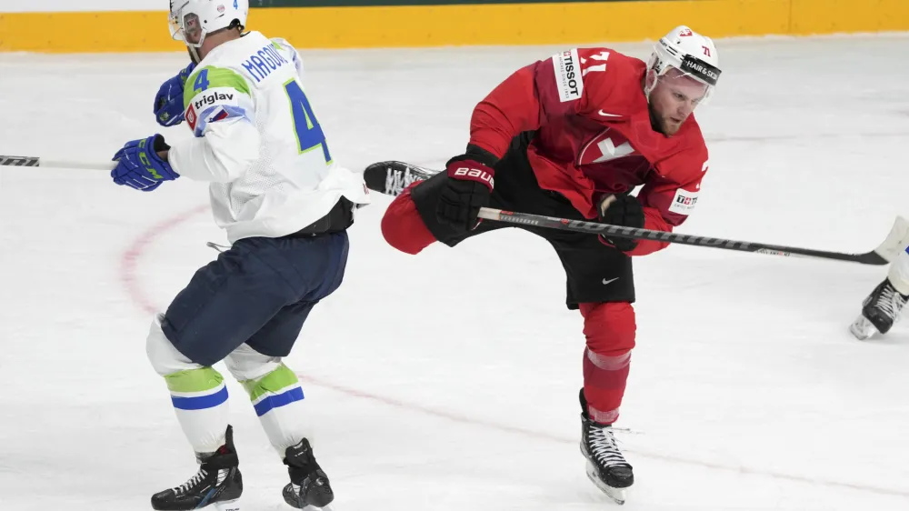 Tanner Richard of Switzerland, right, fights for a puck with Aleksandar Magovac of Slovenia during the group B match between Switzerland and Slovenia at the ice hockey world championship in Riga, Latvia, Saturday, May 13, 2023. (AP Photo/Roman Koksarov)
