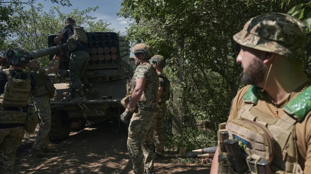 Ukrainian soldiers load rockets into a Grad multiple rocket launcher to fire towards Russian positions in the frontline near Bakhmut, Donetsk region, Ukraine, Wednesday, May 17, 2023. (AP Photo/Libkos)