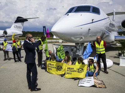 Environmental activists of Stay Grounded and Greenpeace protest by being handcuffed to a aircraft during the European Business Aviation Convention and Exhibition (EBACE), at the Geneve Aeroport in Geneva, Switzerland, Tuesday, May 23, 2023. (Laurent Gillieron/Keystone via AP)