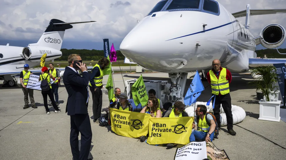 Environmental activists of Stay Grounded and Greenpeace protest by being handcuffed to a aircraft during the European Business Aviation Convention and Exhibition (EBACE), at the Geneve Aeroport in Geneva, Switzerland, Tuesday, May 23, 2023. (Laurent Gillieron/Keystone via AP)