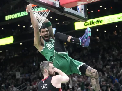 Boston Celtics forward Jayson Tatum, top, dunks as Miami Heat forward Kevin Love defends during the first half in Game 5 of the NBA basketball Eastern Conference finals series Thursday, May 25, 2023, in Boston. (AP Photo/Charles Krupa)