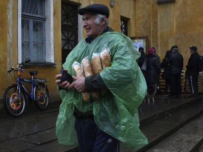 A man carries Ukrainian passport and bread after receiving it at humanitarian aid center in Kramatorsk, Ukraine, Wednesday, Oct. 26, 2022. (AP Photo/Andriy Andriyenko)