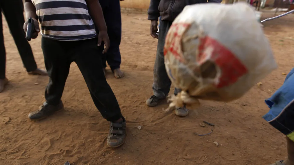 South African kids, using a ragged ball, one holding a toy weapon, play soccer in Thokoza, on the outskirts of Johannesburg, South Africa, Thursday, July 1, 2010. (AP Photo/Hassan Ammar)