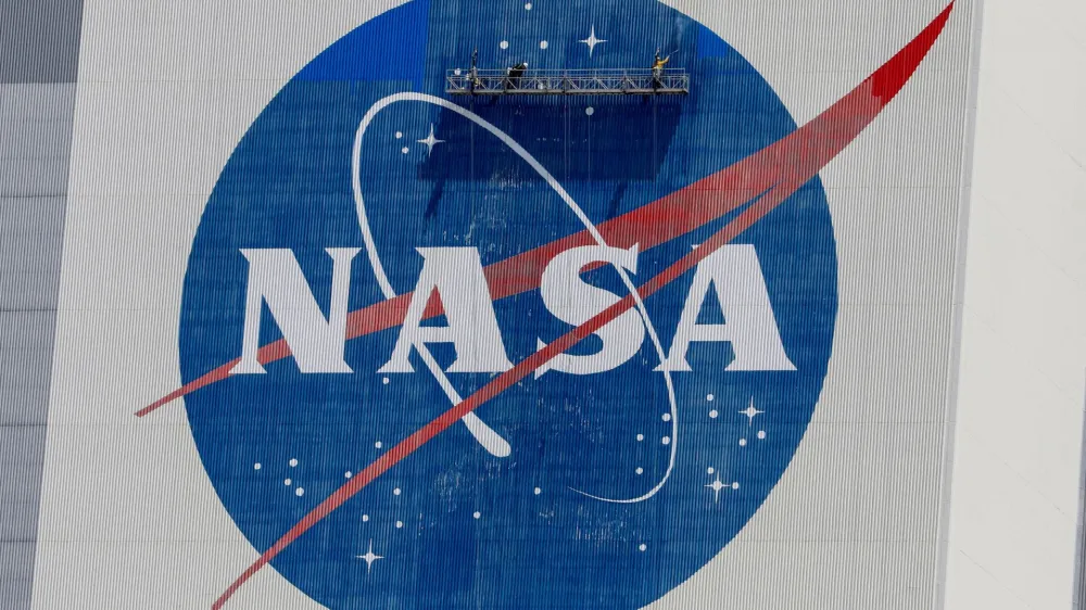 FILE PHOTO: Workers pressure wash the logo of NASA on the Vehicle Assembly Building before SpaceX will send two NASA astronauts to the International Space Station aboard its Falcon 9 rocket, at the Kennedy Space Center in Cape Canaveral, Florida, U.S., May 19, 2020. REUTERS/Joe Skipper/File Photo