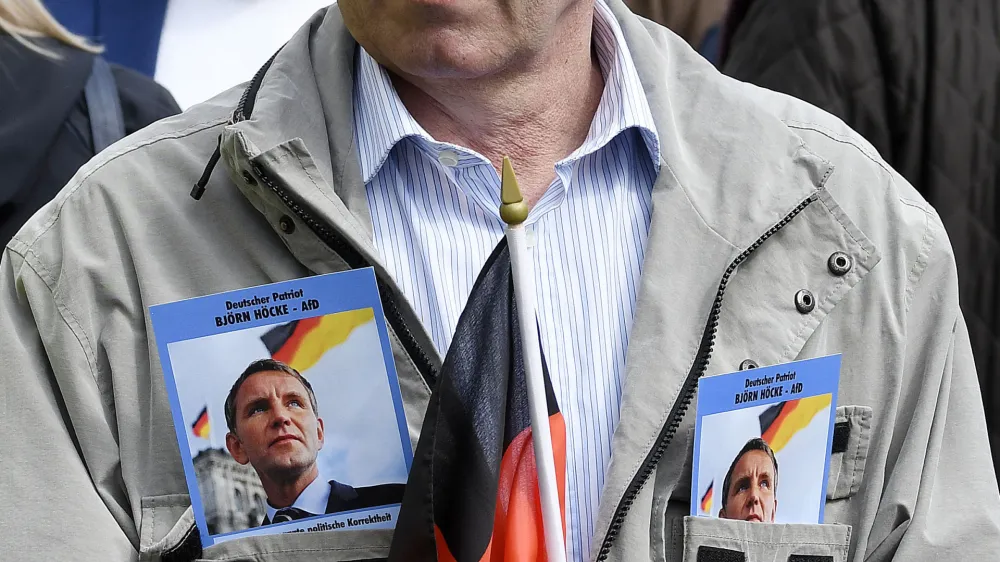 ﻿File---File picture taken May 1, 2019 shows a supporter of Alternative for Germany party AfD waiting for the beginning of a rally in Erfurt, Germany. Flyers in jacket show leader of Thuringia's AfD faction Bjoern Hoecke. German media outlets are reporting the country's domestic intelligence agency has put the opposition Alternative for Germany party under observation under suspicion of extreme right sympathies. (AP Photo/Jens Meyer, file)