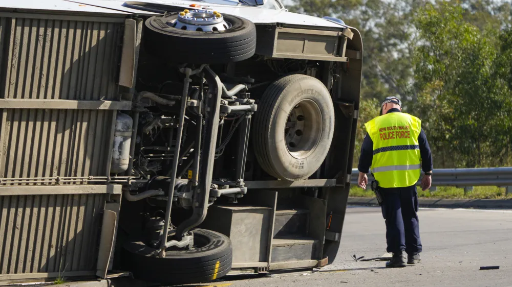 Police inspect underneath a bus that rolled onto its side near Greta in the Hunter Valley, north of Sydney, Australia, Monday, June 12, 2023. The bus carrying wedding guests rolled over on a foggy night in Australia's wine country, killing and injuring multiple people, police said. (AP Photo/Mark Baker)