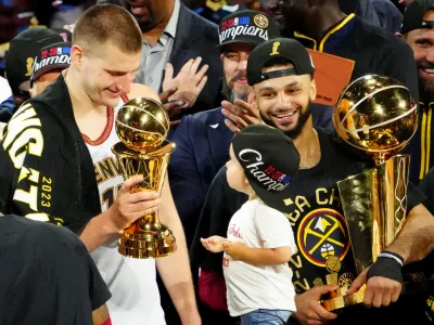 Jun 12, 2023; Denver, Colorado, USA; Denver Nuggets center Nikola Jokic (15) celebrates with the Bill Russell NBA Finals MVP Award as guard Jamal Murray (27) holds the Larry O'Brien Trophy after the Nuggets won the 2023 NBA Championship against the Miami Heat at Ball Arena. Mandatory Credit: Ron Chenoy-USA TODAY Sports