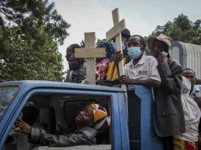 Relatives ride in the back of a truck with the coffins of villagers who were killed by suspected rebels as they retreated from Saturday's attack on the Lhubiriha Secondary School, outside the mortuary of the hospital in Bwera, Uganda Sunday, June 18, 2023. Ugandan authorities have recovered the bodies of 41 people including 38 students who were burned, shot or hacked to death after suspected rebels attacked the school in Mpondwe near the border with Congo, according to the local mayor. (AP Photo/Hajarah Nalwadda)