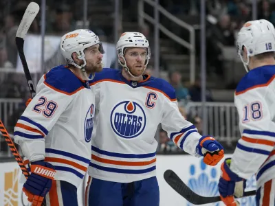 Edmonton Oilers center Connor McDavid, middle, celebrates with center Leon Draisaitl, left, and left wing Zach Hyman after scoring against the San Jose Sharks during the second period of an NHL hockey game in San Jose, Calif., Friday, Jan. 13, 2023. (AP Photo/Godofredo A. V&aacute;squez)