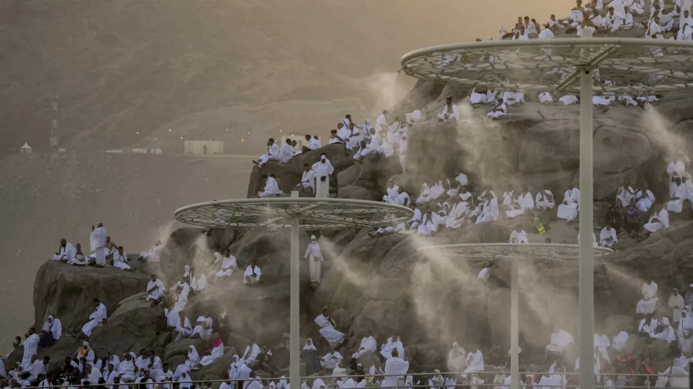 Water mist is sprayed on Muslim pilgrims as they pray on the rocky hill known as the Mountain of Mercy, on the Plain of Arafat, during the annual Hajj pilgrimage, near the holy city of Mecca, Saudi Arabia, Tuesday, June 27, 2023. Around two million pilgrims are converging on Saudi Arabia's holy city of Mecca for the largest Hajj since the coronavirus pandemic severely curtailed access to one of Islam's five pillars. (AP Photo/Amr Nabil)