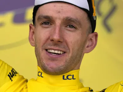 Britain's Adam Yates wearing the overall leader's yellow jersey, celebrates on the podium of the first stage of the Tour de France cycling race over 182 kilometers (113 miles) with start and finish in Bilbao, Spain, Saturday, July 1, 2023.. (AP Photo/Thibault Camus)