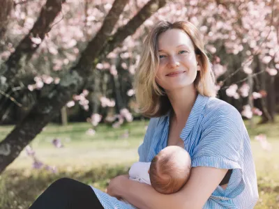 Beautiful mother breastfeeding baby. Young woman breast feeding her newborn baby. Concept of lactation infant, postpartum period, natural motherhood. Mother and baby on nature outdoors.