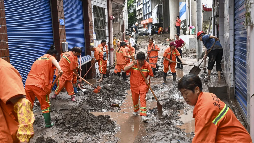 In this photo released by China's Xinhua News Agency, workers clean up silt and mud along a street in the Wanzhou district of Chongqing, China, Tuesday, July 4, 2023. More than a dozen people have been killed by floods in southwestern China as seasonal torrents hit mountain areas, authorities said Wednesday. (Ran Mengjun/Xinhua via AP)