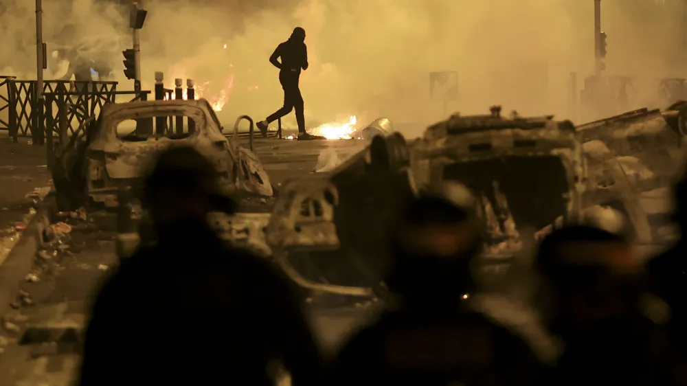 FILE - A demonstrator runs on the third night of protests sparked by the fatal police shooting of a 17-year-old driver in the Paris suburb of Nanterre, France, Friday, June 30, 2023. After more than 3,400 arrests and signs that the violence is now abating, France is once again facing a reckoning. (AP Photo/Aurelien Morissard, File)