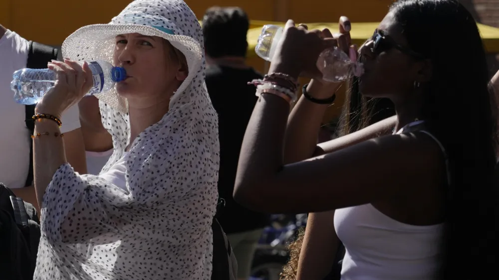 Tourists sips cold water as they shelter from a hot sunny afternoon near the Rome's Colosseum, Wednesday, July 5, 2023. According to weather forecasts temperatures are expected to rise on the upcoming week end reaching in some part of the country 45 Celsius degrees (113 Fahrenheit). (AP Photo/Gregorio Borgia)