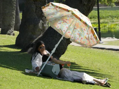People enjoy refreshments under the shade at the Echo Park Lake in Los Angeles Wednesday, July 5, 2023. Wednesday could become the third straight day that global temperatures unofficially hit a record-breaking high. In the U.S., heat advisories include portions of western Oregon, inland far northern California, central New Mexico, Texas, Florida and the coastal Carolinas, according to the National Weather Service Weather Prediction Center. (AP Photo/Damian Dovarganes)