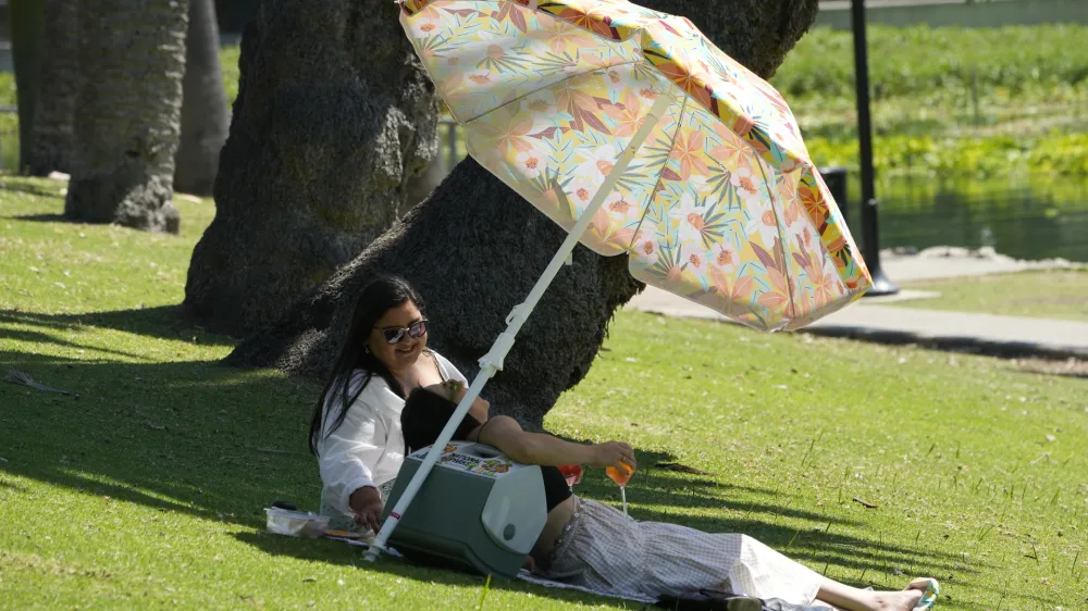 People enjoy refreshments under the shade at the Echo Park Lake in Los Angeles Wednesday, July 5, 2023. Wednesday could become the third straight day that global temperatures unofficially hit a record-breaking high. In the U.S., heat advisories include portions of western Oregon, inland far northern California, central New Mexico, Texas, Florida and the coastal Carolinas, according to the National Weather Service Weather Prediction Center. (AP Photo/Damian Dovarganes)