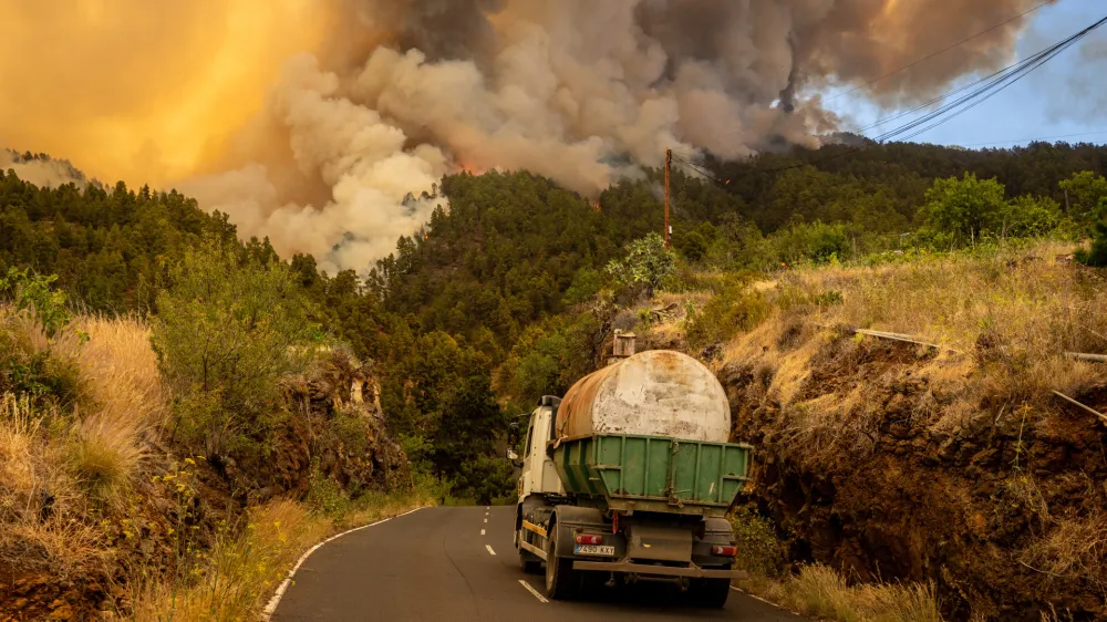 15 July 2023, Spain, La Palms: A tanker truck wade as smoke billows from a forest fire in La Palma. Photo: Europa Press/EUROPA PRESS/dpa