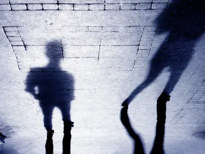 ﻿Upside down shadow of two person on pattered sidewalk, in black and white