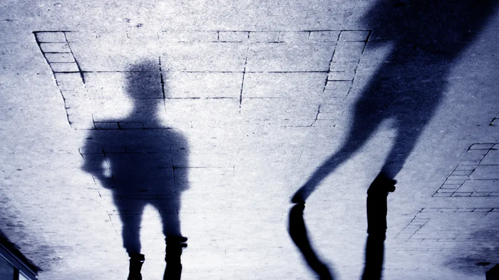 ﻿Upside down shadow of two person on pattered sidewalk, in black and white