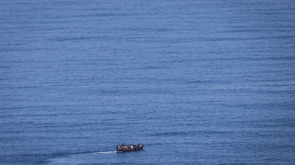 PRODUCTION - 29 June 2023, Italy, Lampedusa: Migrants steer a boat from the northern coast of Africa across the Mediterranean Sea towards the Italian island of Lampedusa. More and more African refugees are crossing to Italy from Tunisia. Many migrants pay a high price for the journey, not only financially. Photo: Oliver Weiken/dpa