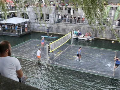 16.08.2022 - Ljubljana: Odbojkarski spektakel na vodi<br>Platforma na reki z igriščem dimenzij 7 krat 14 metrov je potopljena 10 centimetrov pod vodno gladino, igrišče pa je označeno s svetlobnimi črtami.<br>