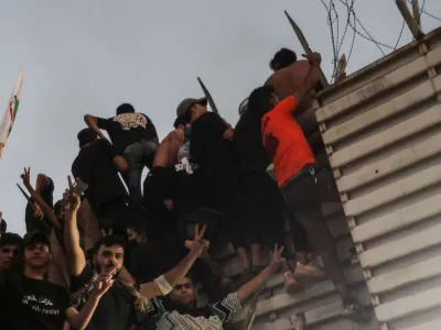 Protesters climb a fence as they gather near the Swedish embassy in Baghdad hours after the embassy was stormed and set on fire ahead of an expected Koran burning in Stockholm, in Baghdad, Iraq, July 20, 2023. REUTERS/Ahmed Saad   TPX IMAGES OF THE DAY