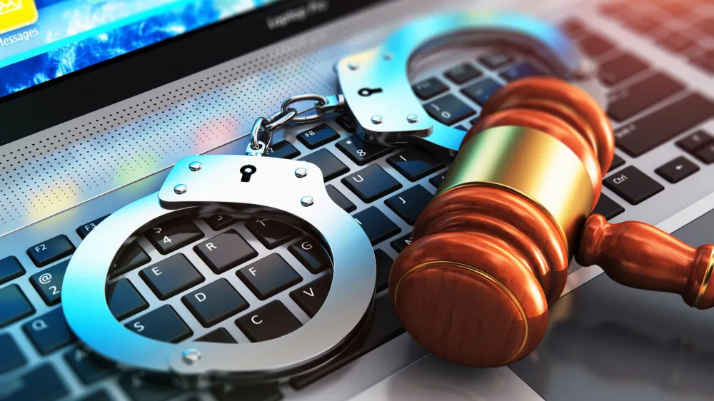 Creative abstract cyber crime, online piracy and internet web hacking concept: 3D render illustration of the macro view of metal handcuffs and wooden judge mallet, gavel or hammer on laptop notebook computer keyboard with selective focus effect