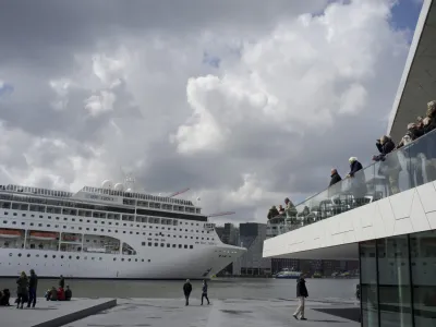 FILE - People visiting the new EYE Film Instute take pictures of the MSC Lirica, a Panama-registered cruise ship passing on IJ river in Amsterdam, Netherlands, April 21, 2012. Amsterdam municipality wants to move a cruise liner terminal out of the heart of the historic capital as the latest step in its ongoing battle against pollution and hoards of tourists clogging its narrow, cobbled streets, it was announced Friday, July 21, 2023. The Dutch capital is one of the many picturesque European cities grappling with how to manage visitor numbers that are again soaring in the aftermath of shutdowns during the coronavirus pandemic. (AP Photo/Peter Dejong, file)