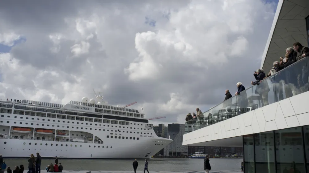 FILE - People visiting the new EYE Film Instute take pictures of the MSC Lirica, a Panama-registered cruise ship passing on IJ river in Amsterdam, Netherlands, April 21, 2012. Amsterdam municipality wants to move a cruise liner terminal out of the heart of the historic capital as the latest step in its ongoing battle against pollution and hoards of tourists clogging its narrow, cobbled streets, it was announced Friday, July 21, 2023. The Dutch capital is one of the many picturesque European cities grappling with how to manage visitor numbers that are again soaring in the aftermath of shutdowns during the coronavirus pandemic. (AP Photo/Peter Dejong, file)