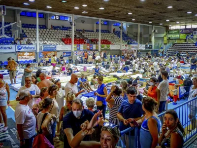 Evacuees sit inside a stadium following their evacuation during a forest fire on the island of Rhodes, Greece, Sunday, July 23, 2023. Some 19,000 people have been evacuated from the Greek island of Rhodes as wildfires continued burning for a sixth day on three fronts, Greek authorities said on Sunday. (Argyris Mantikos/Eurokinissi via AP)