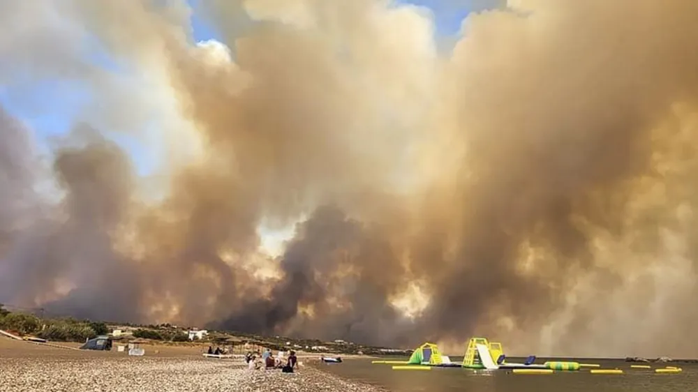 Clouds of smoke from a forest fire rise to the sky on the island of Rhodes, Greece, Saturday, July 22, 2023. A large blaze burning on the Greek island of Rhodes for the fifth day has forced authorities to order an evacuation of four locations, including two seaside resorts. (Rhodes.Rodos via AP)