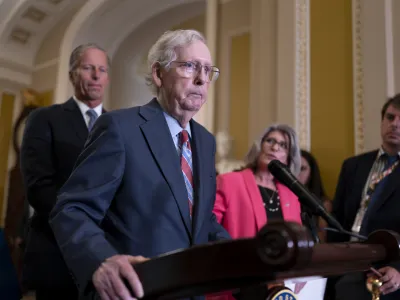 Senate Minority Leader Mitch McConnell, R-Ky., joined at left by Sen. John Thune, R-S.D., and Sen. Joni Ernst, R-Iowa, seems to freeze at the microphones as he arrived for a news conference at the Capitol in Washington, Wednesday, July 26, 2023. McConnell went to his office for a few minutes and returned to speak with reporters. (AP Photo/J. Scott Applewhite)