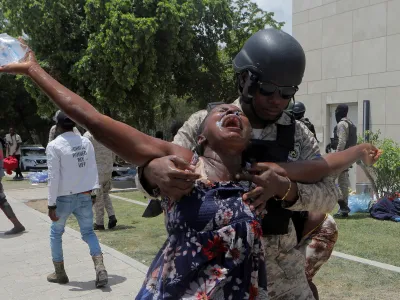 An officer of the Haitian National Police holds a woman affected by tear gas after the police cleared a camp of people escaping the threat of armed gangs, in front of the U.S. Embassy, in Port-au-Prince, Haiti July 25, 2023. REUTERS/Ralph Tedy Erol