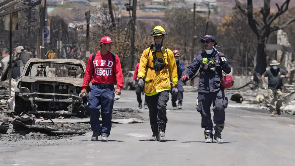 Members of a search and rescue team walk along a street on Saturday, Aug. 12, 2023, in Lahaina, Hawaii. (AP Photo/Rick Bowmer)