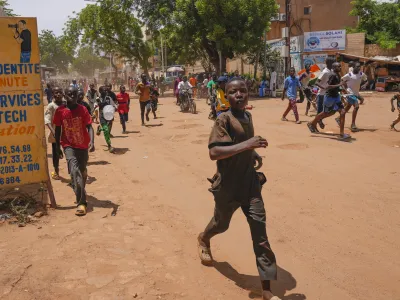 Children run in the streets of Niamey, Niger, Sunday, Aug. 13, 2023. People marched, biked and drove through downtown Niamey, chanting "down with France" and expressing anger at ECOWAS. (AP Photo/Sam Mednick)