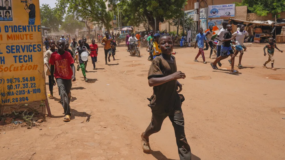 Children run in the streets of Niamey, Niger, Sunday, Aug. 13, 2023. People marched, biked and drove through downtown Niamey, chanting "down with France" and expressing anger at ECOWAS. (AP Photo/Sam Mednick)