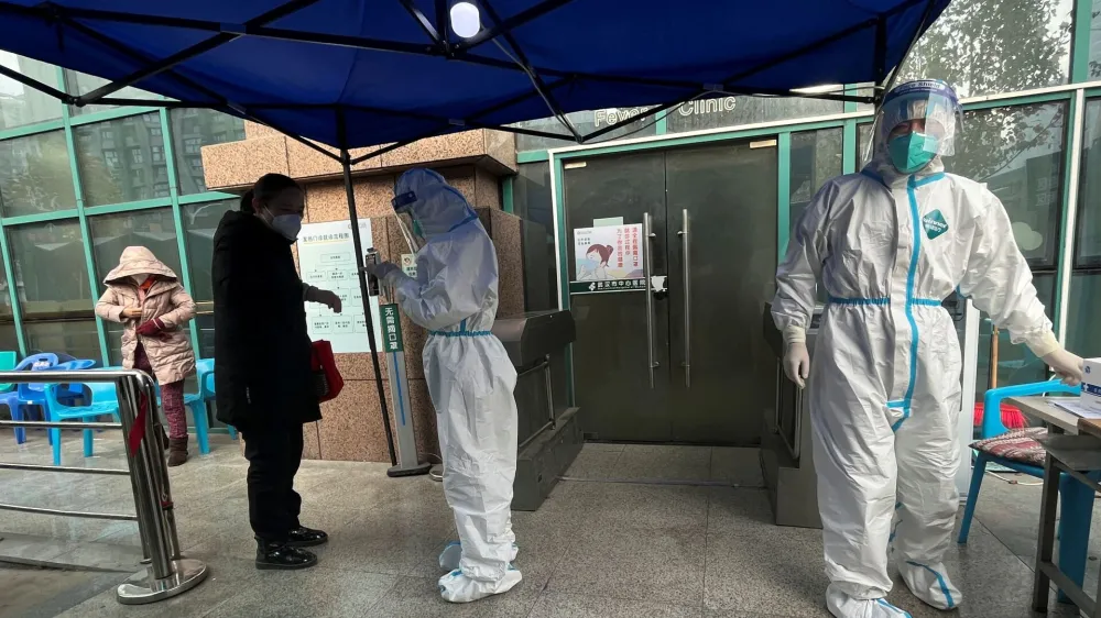 A medical worker in a protective suit checks a thermometer for a patient at the entrance to the fever clinic of the Central Hospital of Wuhan, amid of the coronavirus disease (COVID-19) outbreak, in Wuhan, Hubei province, China December 31, 2022. REUTERS/Tingshu Wang