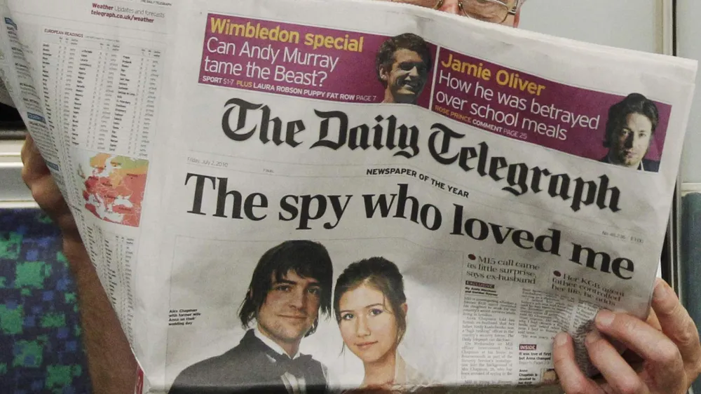 A passenger reads the Daily Telegraph newspaper, featuring a front page interview with the ex-husband of accused Russian spy Anna Chapman, on the underground in London July 2, 2010. Chapman, one of 10 arrested, was denied bail on Monday in New York after U.S. authorities said they broke up a spy ring that carried out deep-cover work in the United States to recruit political sources and gather information for the Russian government. REUTERS/Luke MacGregor (BRITAIN - Tags: CRIME LAW MILITARY POLITICS)