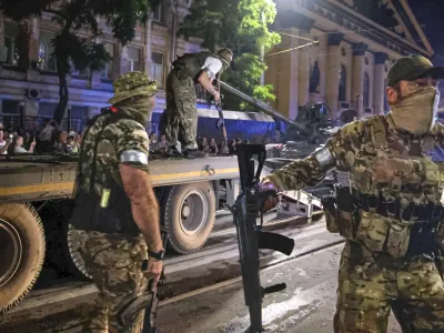 Members of the Wagner Group military company guard an area as other load their tank onto a truck on a street in Rostov-on-Don, Russia, Saturday, June 24, 2023, prior to leaving an area at the headquarters of the Southern Military District. Kremlin spokesman Dmitry Peskov said that Yevgeny Prigozhin's troops who joined him in the uprising will not face prosecution and those who did not will be offered contracts by the Defense Ministry. After the deal was reached Saturday, Prigozhin ordered his troops to halt their march on Moscow and retreat to field camps in Ukraine, where they have been fighting alongside Russian troops. (Vasily Deryugin, Kommersant Publishing House via AP)