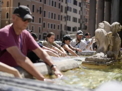 People cool off at a fountain in front of the Pantheon, in Rome, Saturday, Aug. 19, 2023. Italy is facing a heat wave with temperatures in the capital as high as 37 Celsius (98 Farenheit). (AP Photo/Andrew Medichini)