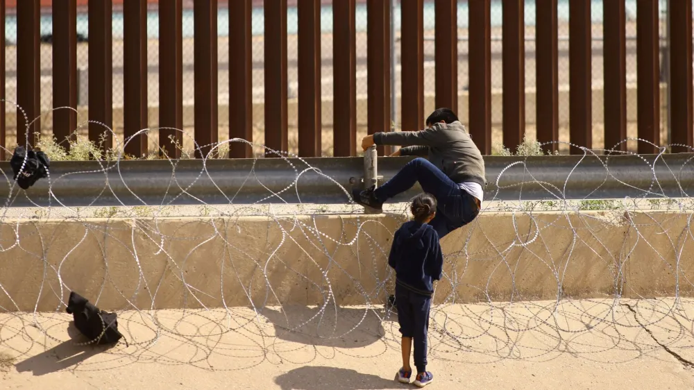 Migrants try to cross through a razor wire fence deployed to inhibit the crossing of migrants into the United States, seen from Ciudad Juarez, Mexico August 28, 2023. REUTERS/Jose Luis Gonzalez